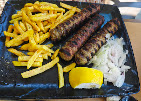 Grilled meat with fries and onions on a slate plate